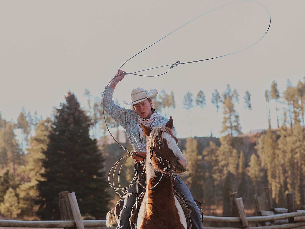 Young man practicing roping during his week-long family Dude Ranch vacations in Arizona
